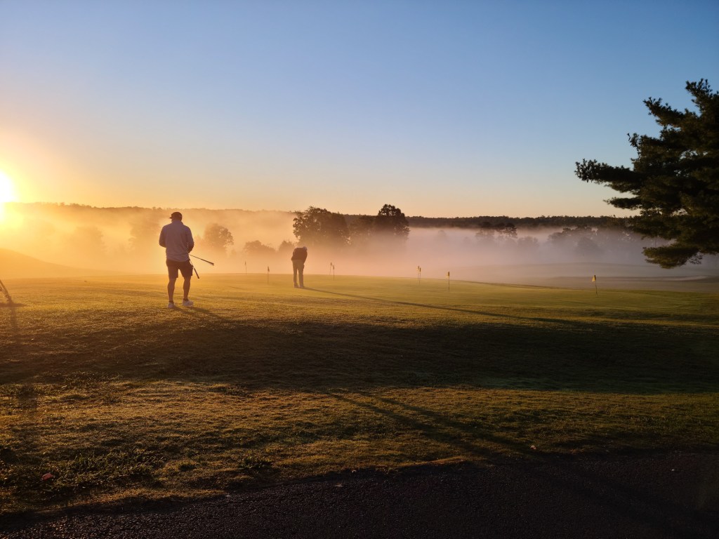 Golfers playing in morning fog 